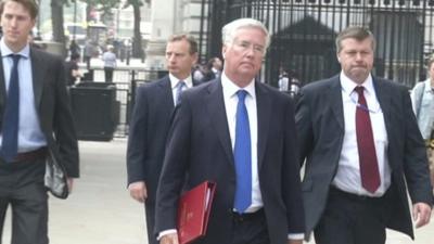 Defence Secretary, Michael Fallon, flanked by officials, arrives for Cobra meeting