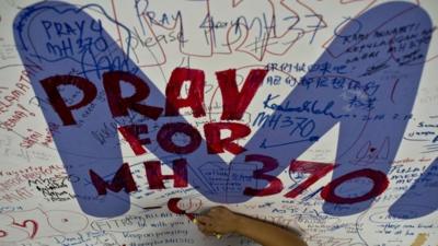 A Malaysia Airlines employee writing a message for passengers of the missing MH370 aeroplane