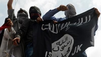 Kashmiri demonstrators hold up a flag of the Islamic State of Iraq and the Levant