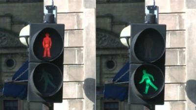 A red pedestrian crossing light and green pedestrian crossing light