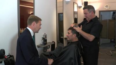 Christian Fraser speaking to hairdresser and customer