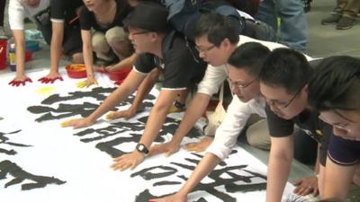 People leaving hand prints on a protest banner in Hong Kong