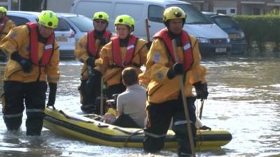 Man in a boat lead by emergency service workers