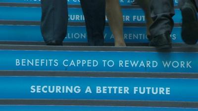 Feet of Conservative party conference delegates walking up stairs with slogans on each step