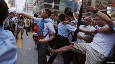 Pro-democracy protester argues with an anti-Occupy Central protester while being kicked by another anti-Occupy Central protester at Hong Kong"s shopping Mongkok district on 3 October 2014