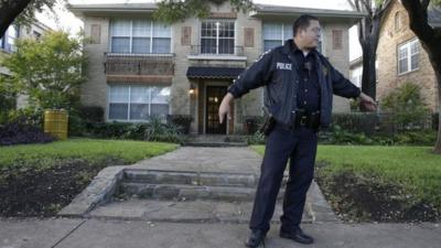 Police stand guard outside the apartment of a hospital worker and a yellow barrel, left, that holds hazardous materials