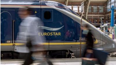 Travellers pass by an Eurostar train