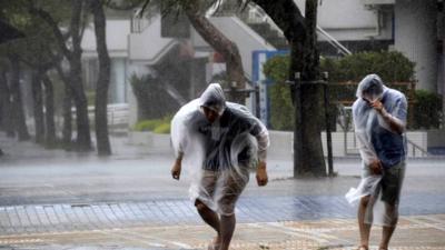 People struggle to walk against strong wind and rain caused by Typhoon Vongfong