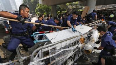 Police officers remove barricades that protesters set up to block off main roads in Central district in Hong Kong