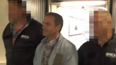 Martin Evans being escorted through Heathrow airport