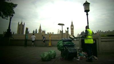 Man clearing rubbish into cart with Westminster in the background