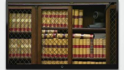 Television screen shows camera nestled amongst books on a shelf within the Royal Courts of Justice