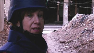 BBC reporter Lyse Doucet in front of an alleyway of rubble in the Syrian city of Aleppo