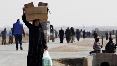 A Syrian refugee carries boxes of aid at Al-Zaatri refugee camp