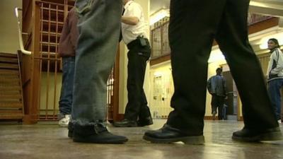 Prisoners being searched by guard