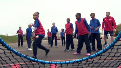 Girl about to throw ball through goal during a game of Fitball