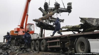 Workers remove wreckage from the MH17 crash site