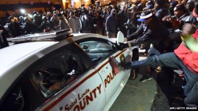 Protesters attack a police car