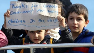 Migrant children display a sign upon their arrival at Crete