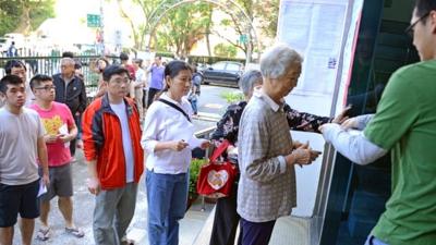 Residents line up for their ID checking before vote at a polling station in Taipei