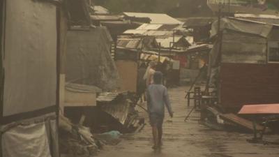 A child walking down a street between some ramshackle shelters in Tacloban