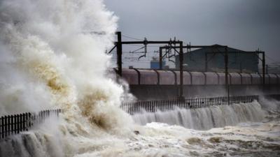 A train passes through Saltcoats as waves crash over the sea wall on December 9, 2014 in Saltcoats, Scotland