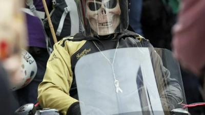 A protester in a skull mask and riot gear