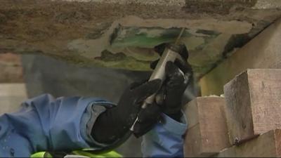 Man working to remove time capsule from concrete slab