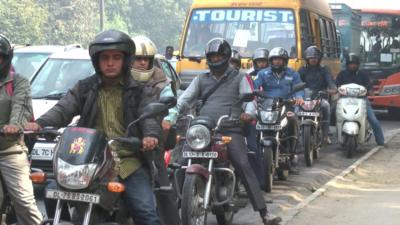 Motorbikes and cars wait at traffic lights in India's capital city Delhi