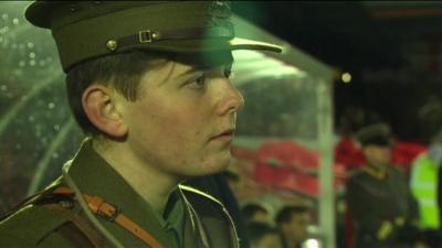 Boy dressed in World War One soldier uniform watching football match