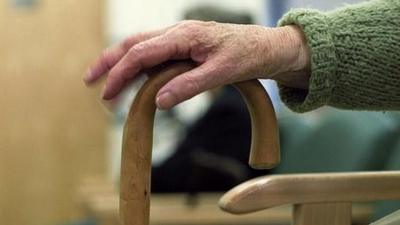 elderly patient's hand on walking stick