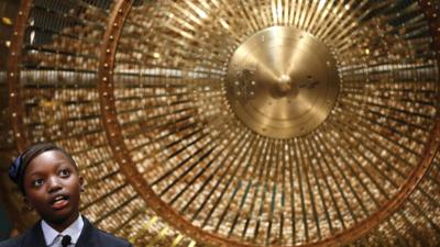 A schoolgirl stands next to a lottery drum during the draw for Spain's Christmas lottery El Gordo in Madrid on 22 December 2014