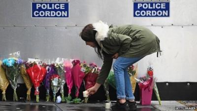 Woman places candle by police cordon