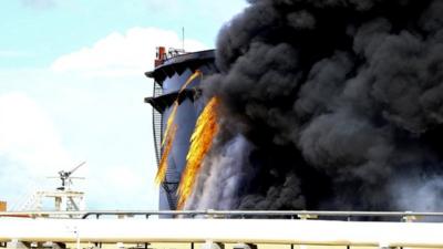 Black smoke billows out of a storage oil tank in the port of Es Sider in Ras Lanuf