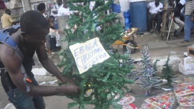 A man arranges a Christmas tree at a shop in Monrovia, Liberia, on 24 December