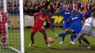 Adebayo Akinfenwa prods home an equaliser for AFC Wimbledon as Liverpool struggle to defend a corner, it's 1-1.