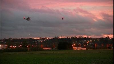 Police helicopters fly over the crime scene.