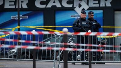 Police officers stand guard at the site of the attack on a kosher market on January 10, 2015 in Paris, France