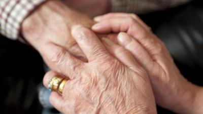 A carer holding an elderly person's hand