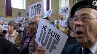 Crowd holding signs saying Je Suis Juif