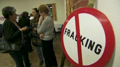 People gathering near an anti fracking banner