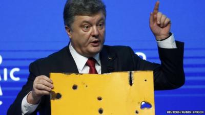 Ukraine President Petro Poroshenko, speaking at World Economic Forum in Davos, holds a fragment of a bus body which he says shows a Russian missile attack on a civilian bus