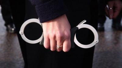 A police recruit at Hendon Police training centre in North London grips a pair of handcuffs