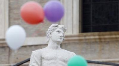 Colored balloons released by children fly next to a statue, at the end of the noon Angelus prayer recited by Pope Francis in St. Peter"s Square at the Vatican, Sunday, Jan. 25, 2015