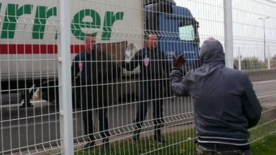 Migrant gestures at police