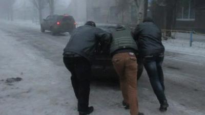 Men pushing a car on ice as they leave Debaltseve