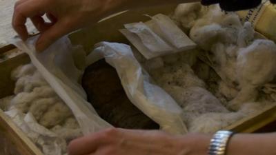 Close up of someone opening up parcel containing ancient Roman scroll