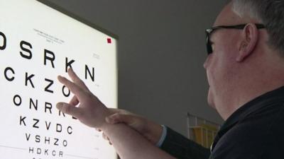 Man with macular degeneration looks at board with letters