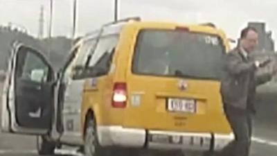 Taxi driver leaves his taxi with arms raised