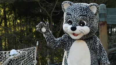 A keeper dressed as a snow leopard